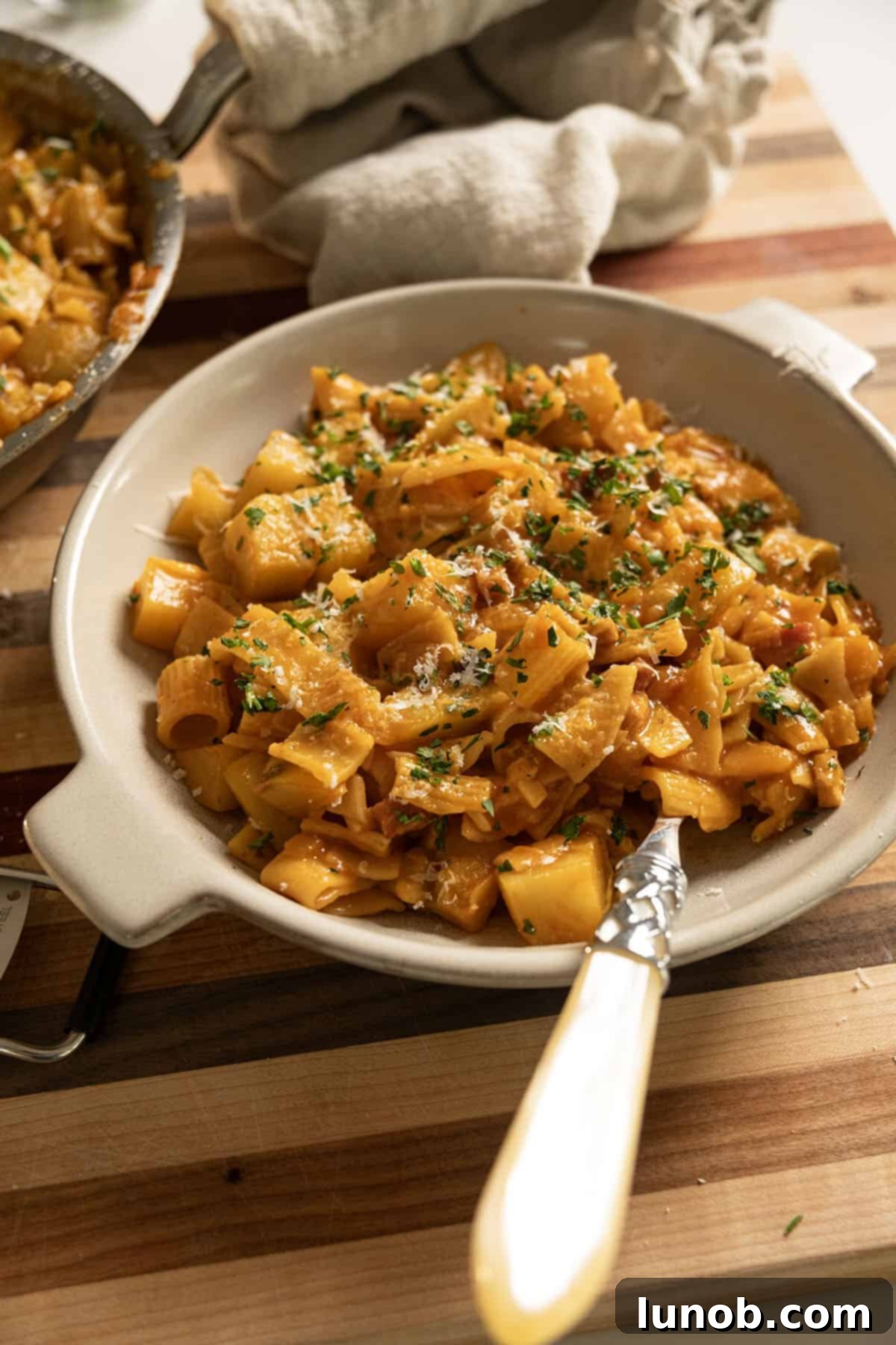 A comforting bowl of Pasta and Potatoes, garnished with fresh parsley and grated Parmesan cheese.