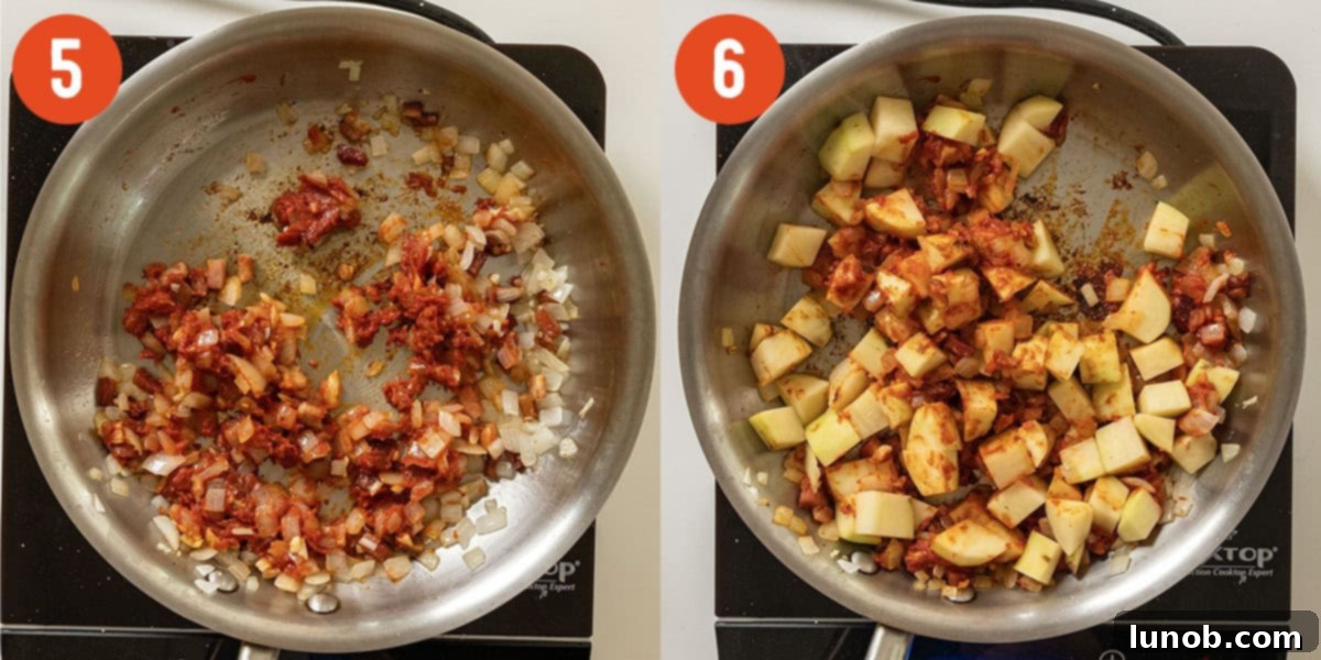 Caramelized tomato paste mixing with chopped potatoes in a saucepan.