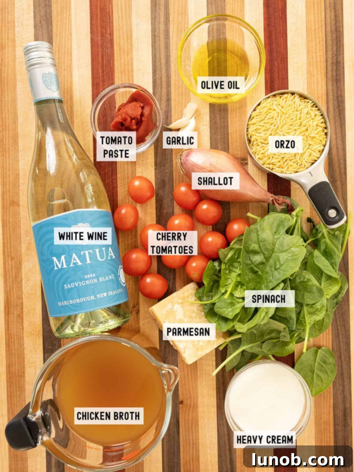 Fresh ingredients laid out for making creamy tomato orzo, including cherry tomatoes, orzo pasta, shallots, garlic, and parmesan cheese.