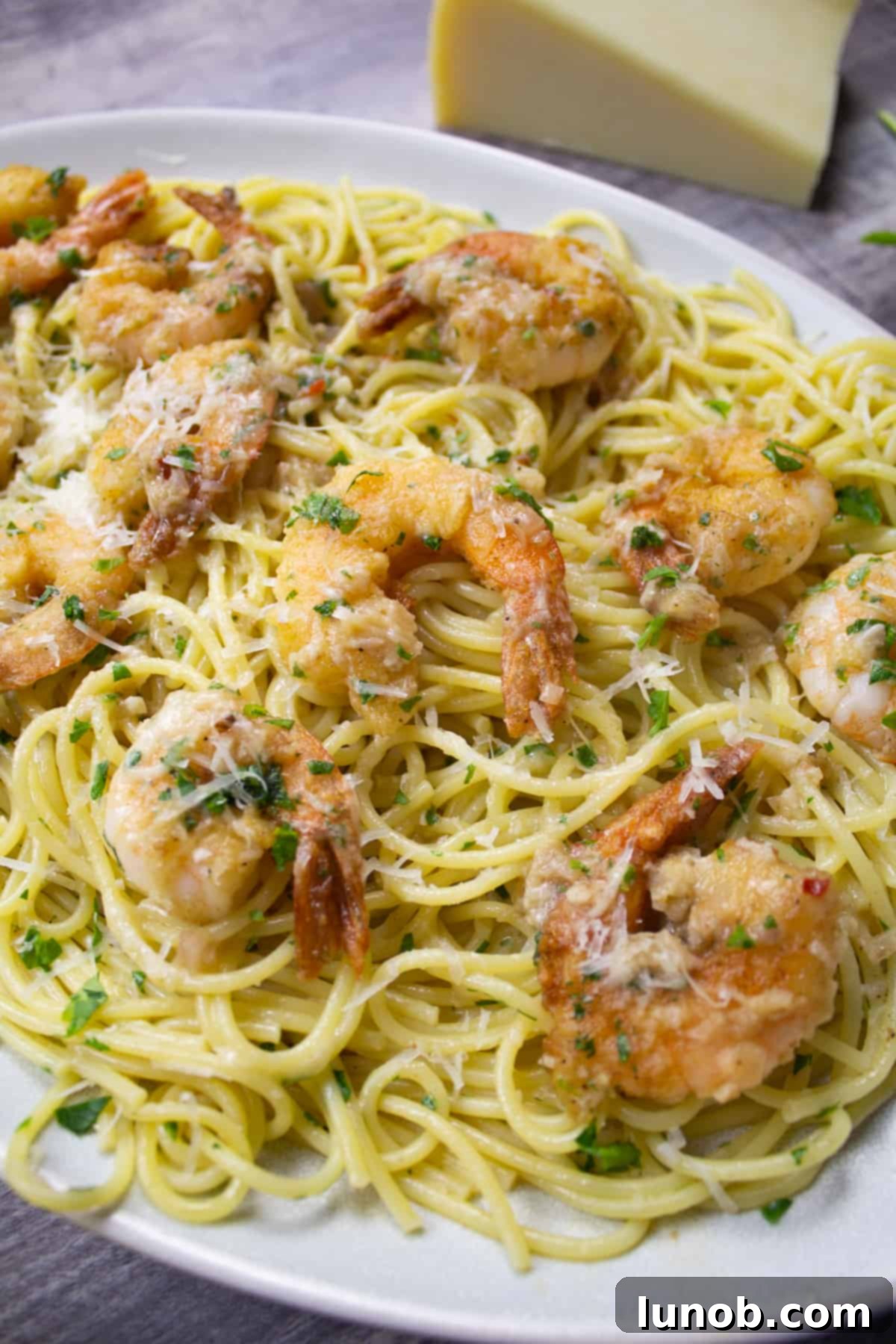 Classic shrimp scampi topped with grated parmesan cheese and fresh parsley, presented beautifully on a white plate.