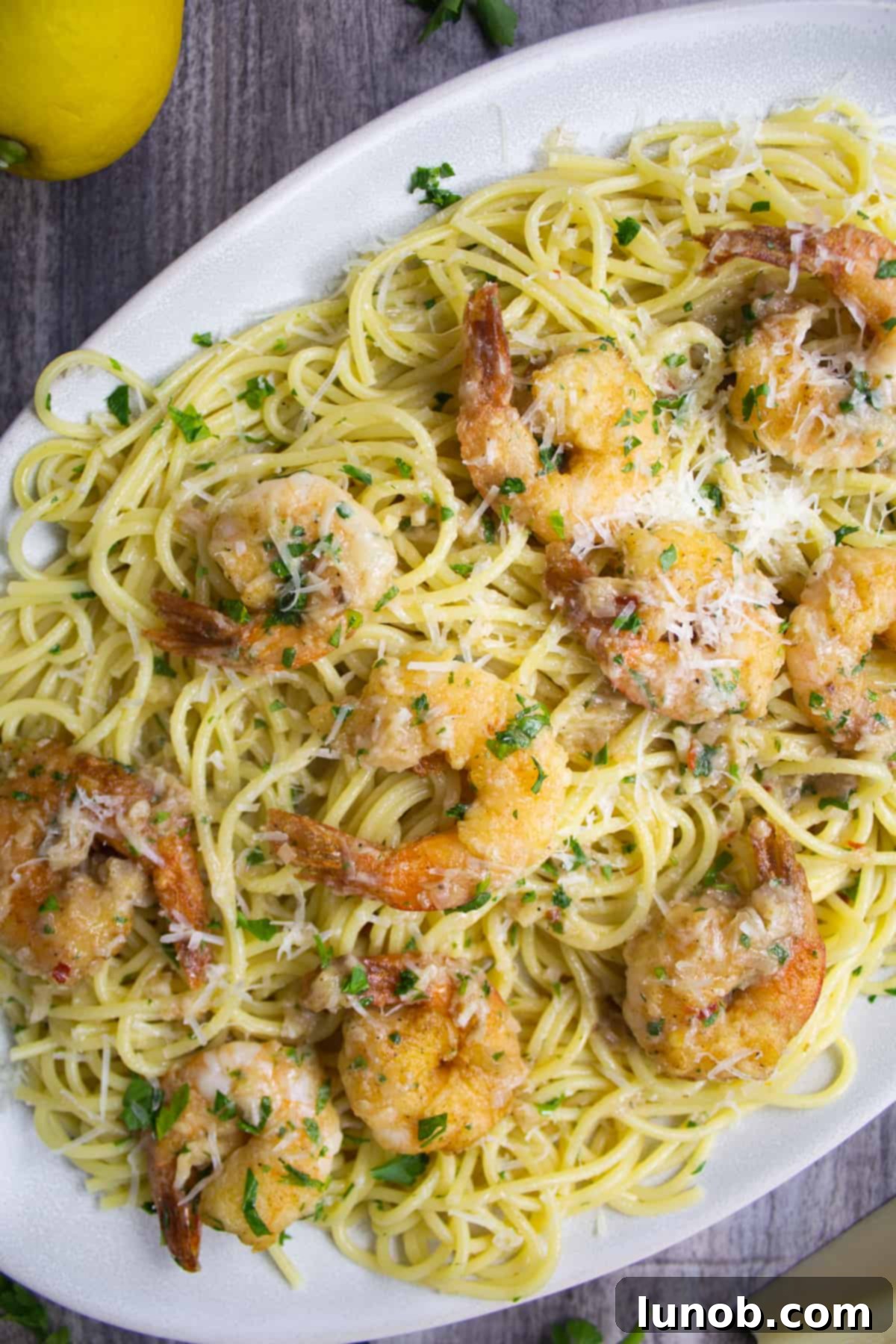 Shrimp scampi served over a bed of spaghetti, garnished with vibrant fresh parsley, ready to be enjoyed.