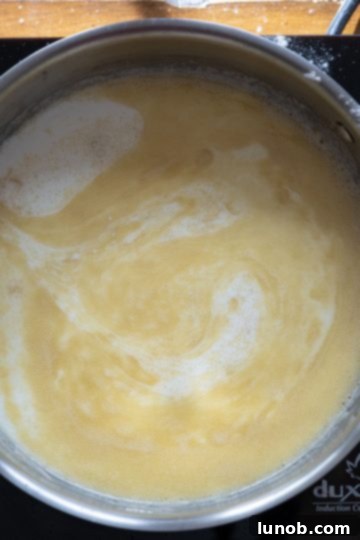 Italian Comfort Mac and Cheese 5 Close up of milk being whisked into a butter-flour roux in a saucepan