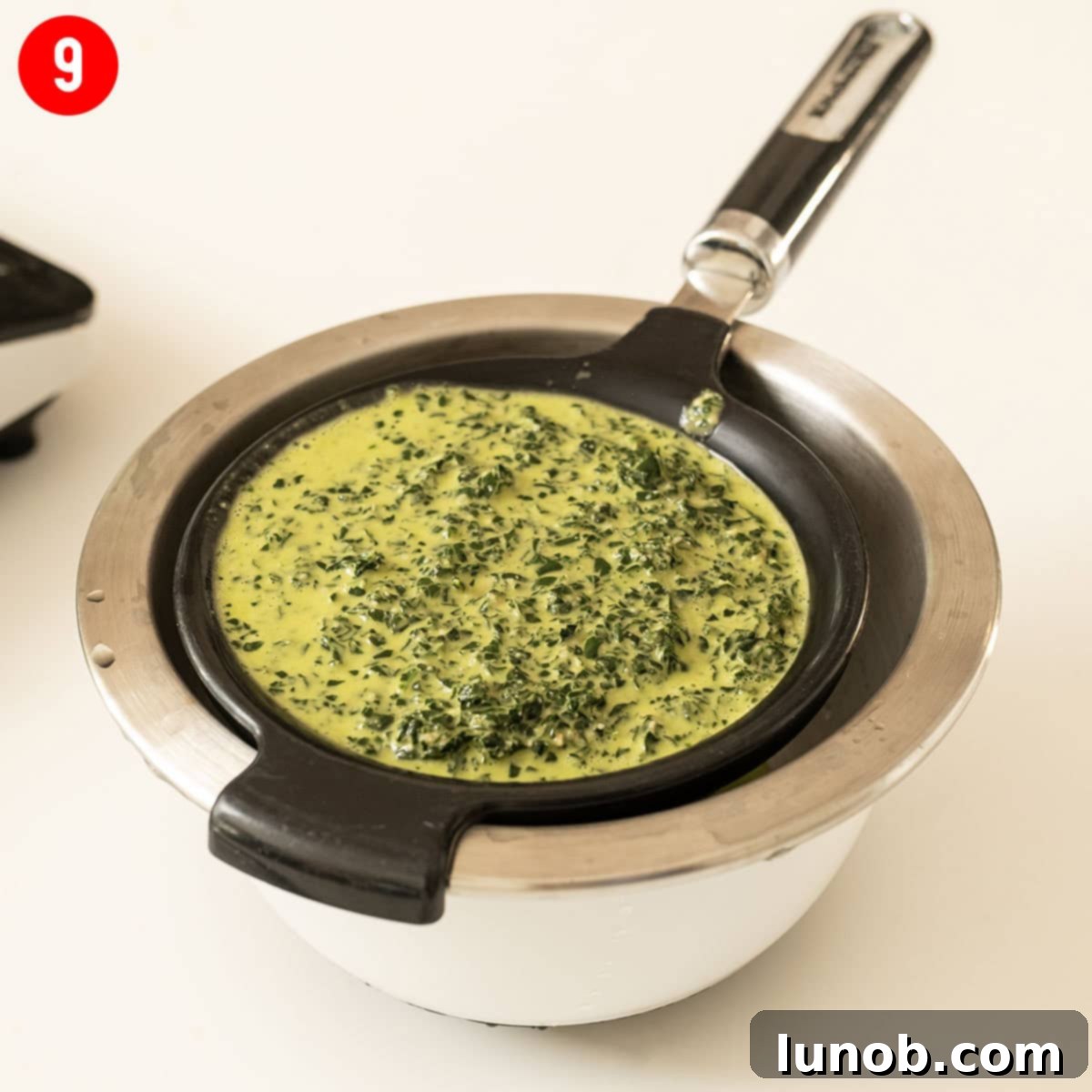 Straining kale pesto in a mesh strainer.