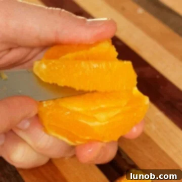 Detailed image of slicing an orange segment, removing pith and membrane.