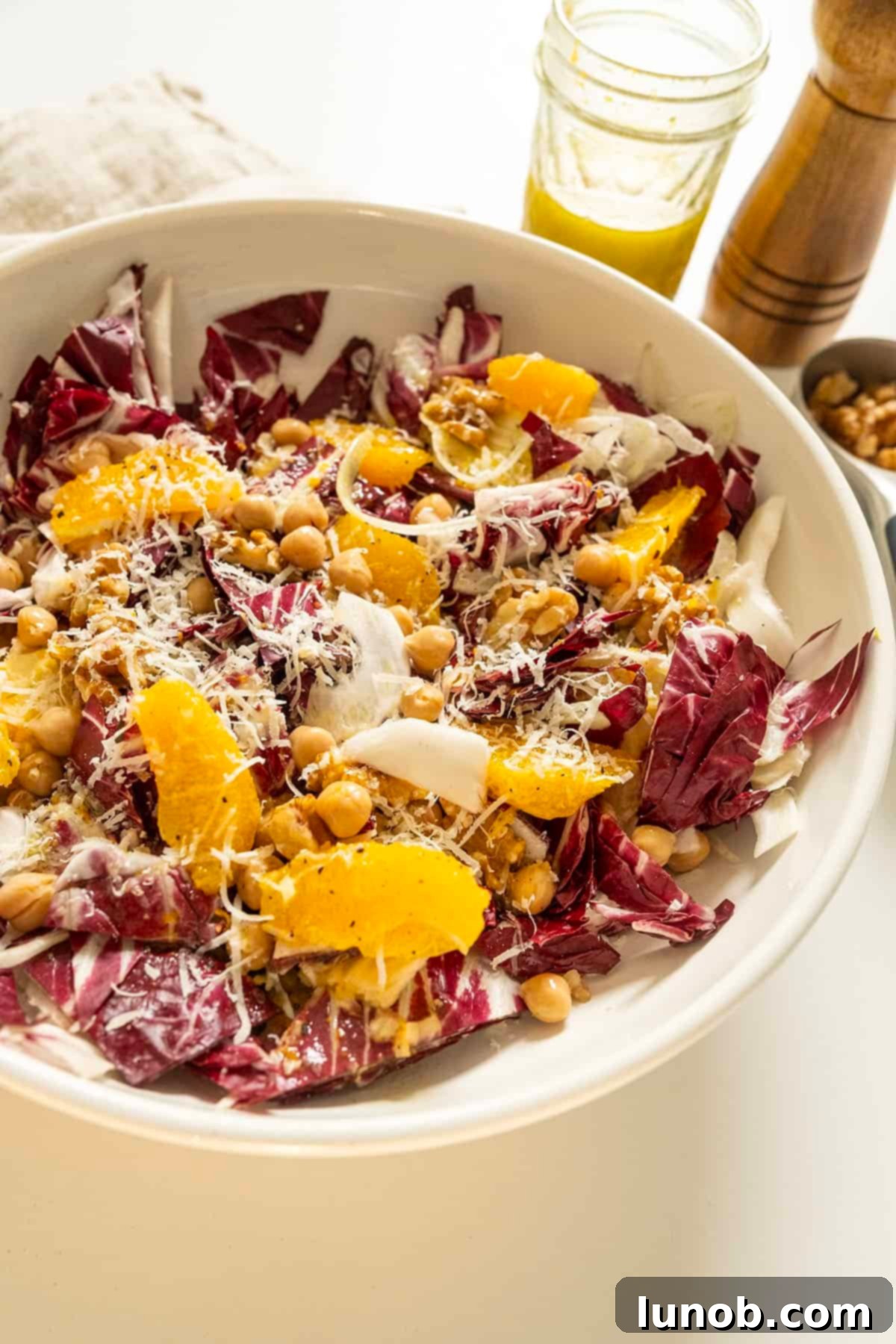 The finished Italian Radicchio Salad, garnished with walnuts, orange segments, and Parmesan, served in a stylish bowl.