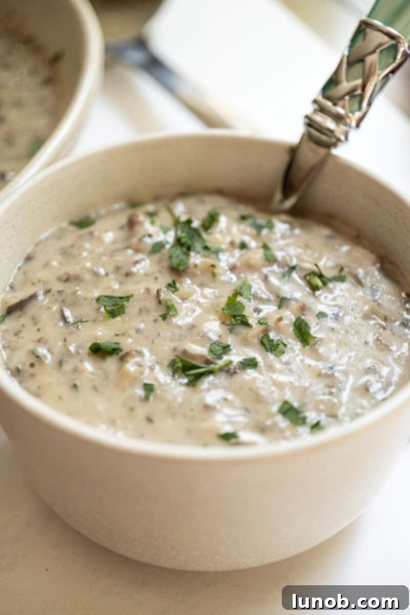 Creamy Mushroom Soup in a bowl, garnished with fresh herbs.