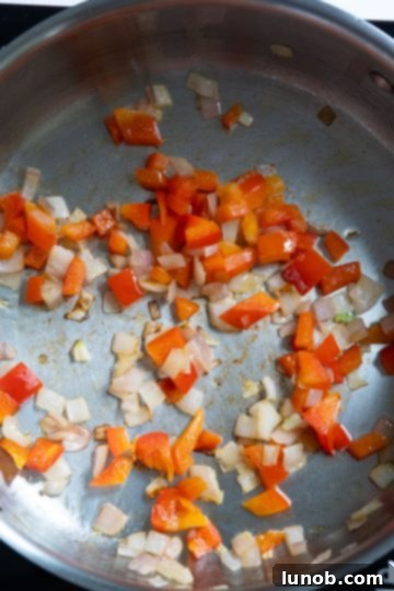 Finely chopped shallots and red pepper sautéing in olive oil in a large pan.