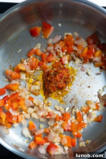 Minced garlic and Calabrian chili peppers added to sautéed shallots and red pepper in a pan.