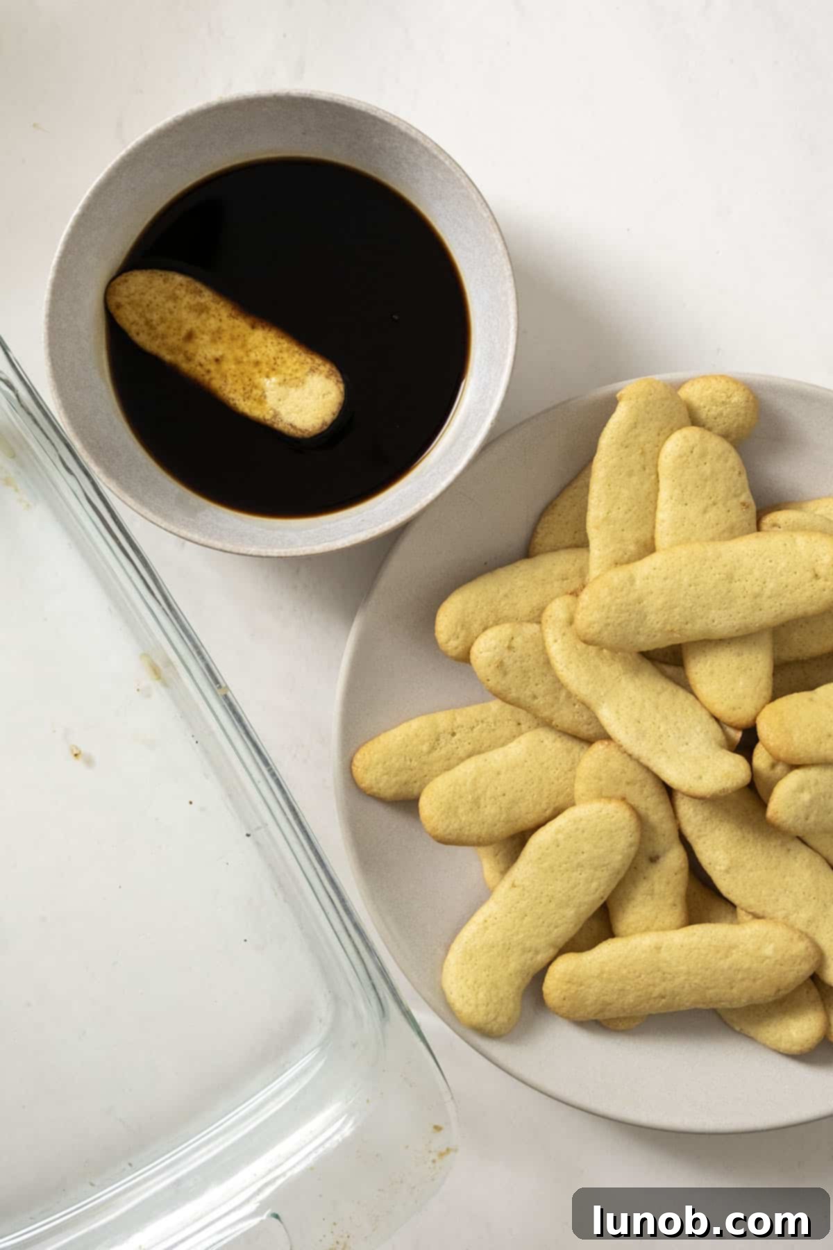 Dipping ladyfingers one by one into the espresso and Disaronno mixture, ensuring even coating.