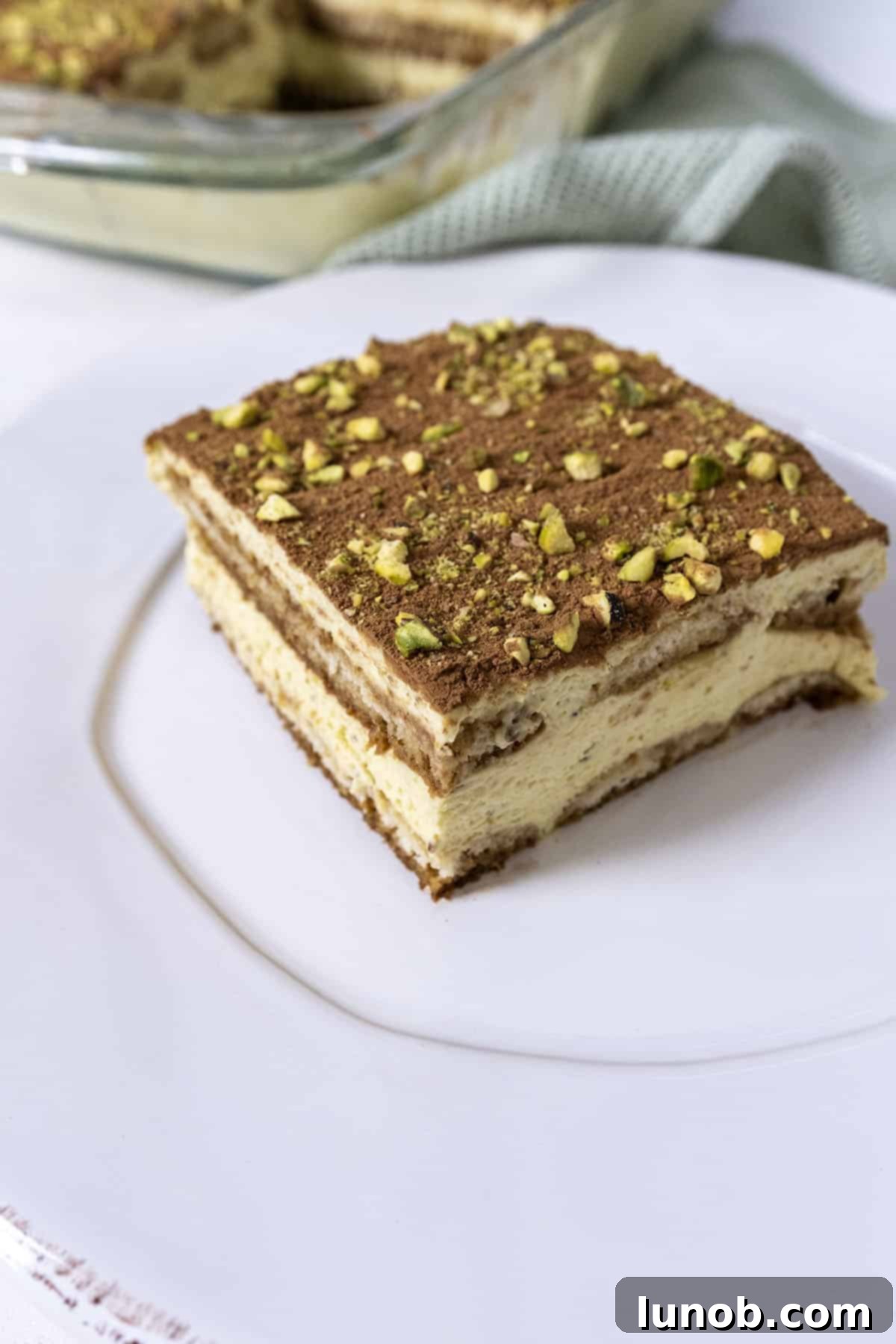 A slice of beautiful Pistachio Tiramisu on a white plate, showcasing its distinct layers.