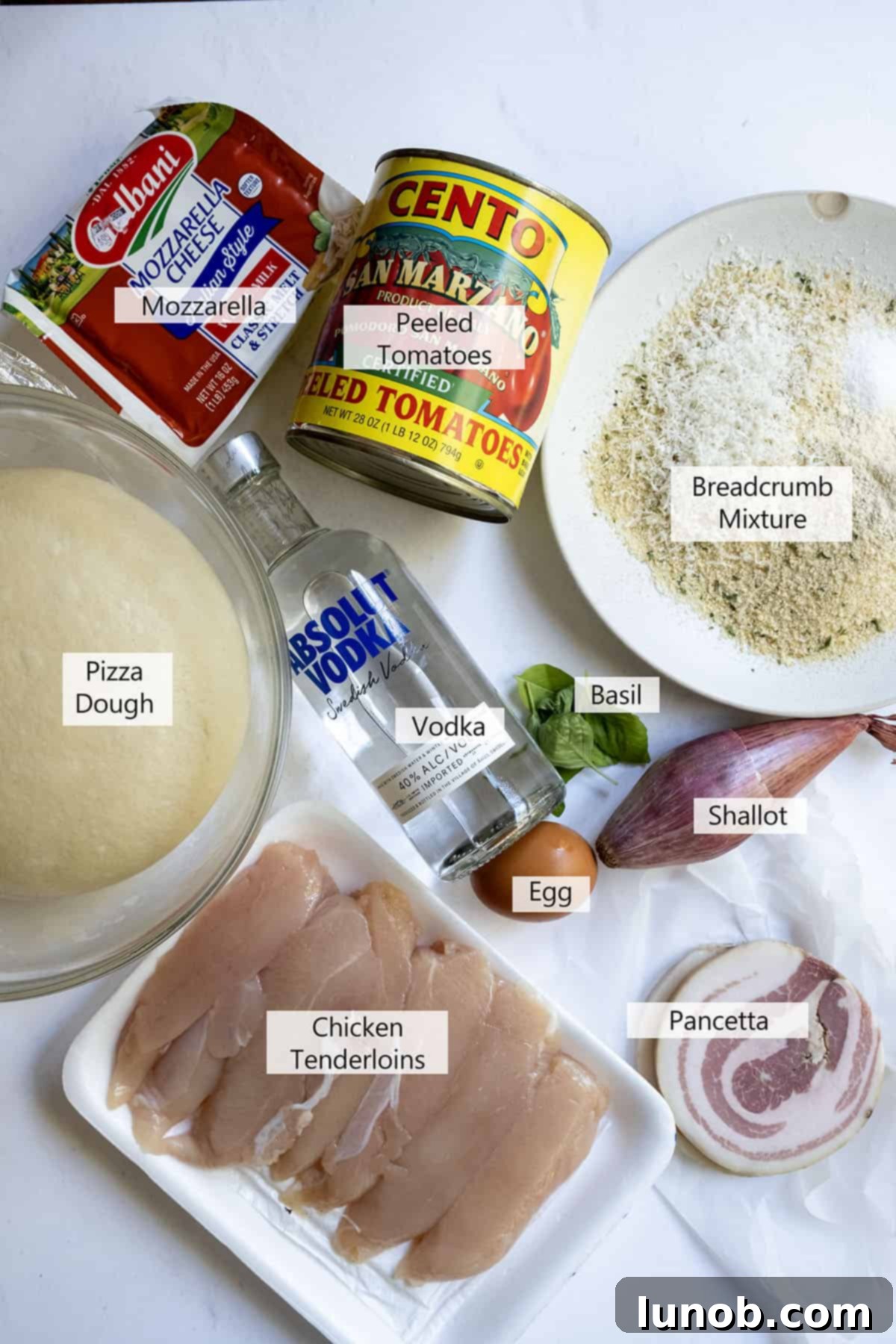 Fresh ingredients laid out for making chicken alla vodka pizza, including dough, tomatoes, and chicken.