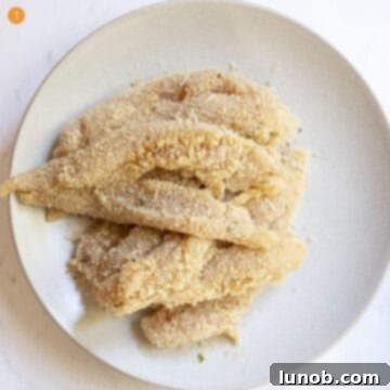 Breaded chicken tenderloins on a plate, ready for frying.