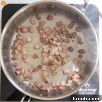 Pancetta frying in a saucepan, rendering its fat.