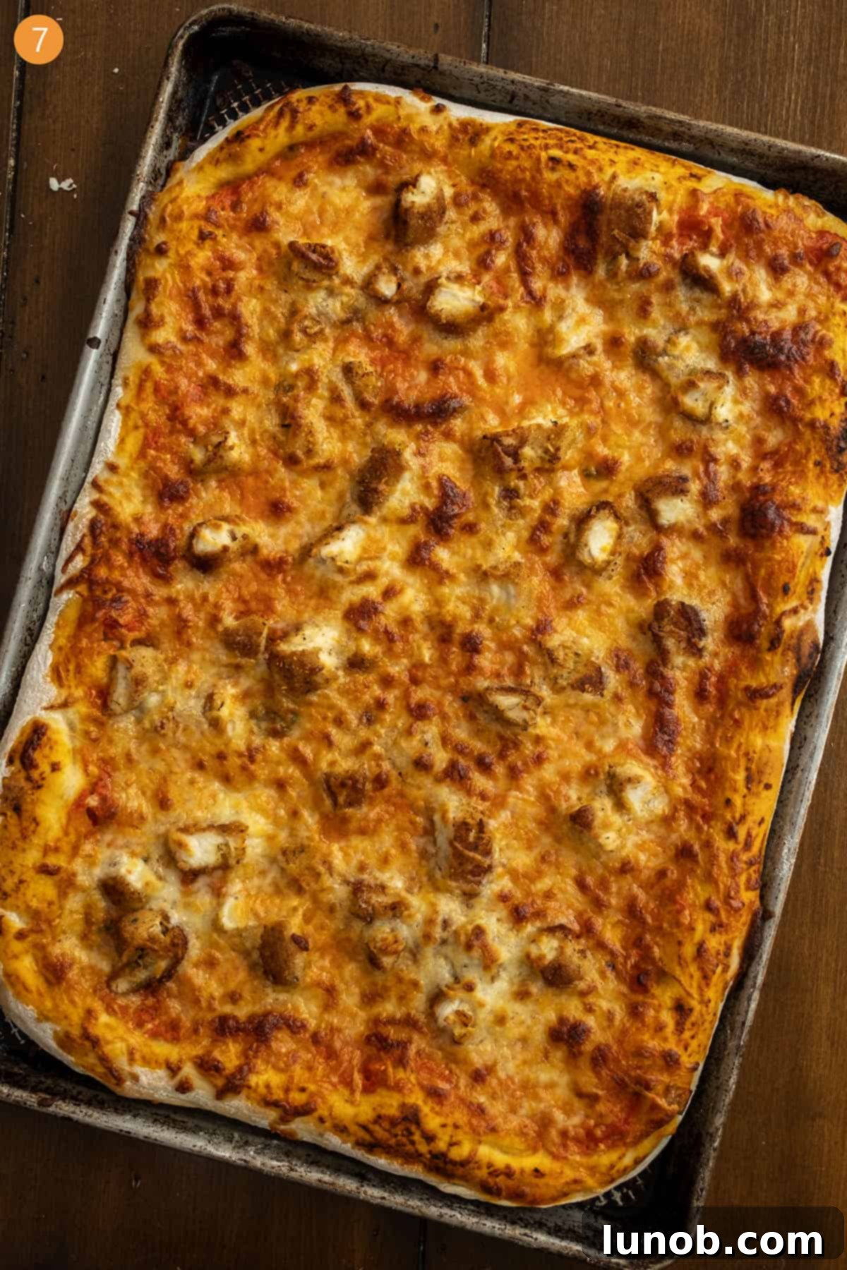 A freshly cooked chicken alla vodka pizza on a cutting board, garnished with fresh basil.