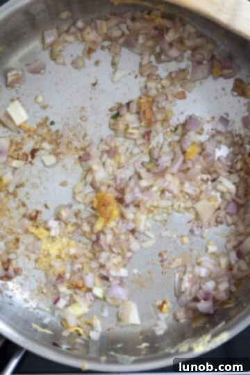 Gourmet Chicken Francese 9 Finely chopped shallots and minced garlic sautéing in a pan, releasing their aromatic compounds to form the base for the lemon-butter sauce.