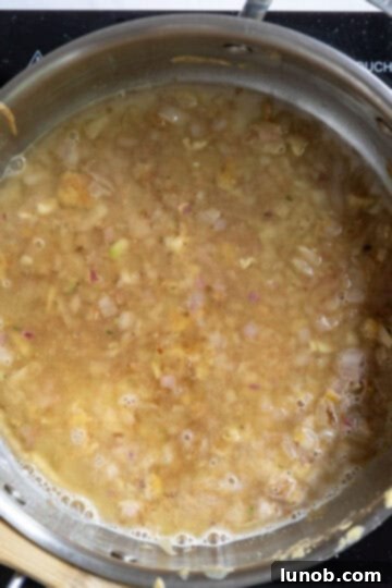 Gourmet Chicken Francese 10 Fresh lemon juice and dry white wine simmering in a saucepan, actively reducing to create a concentrated and flavorful sauce base.