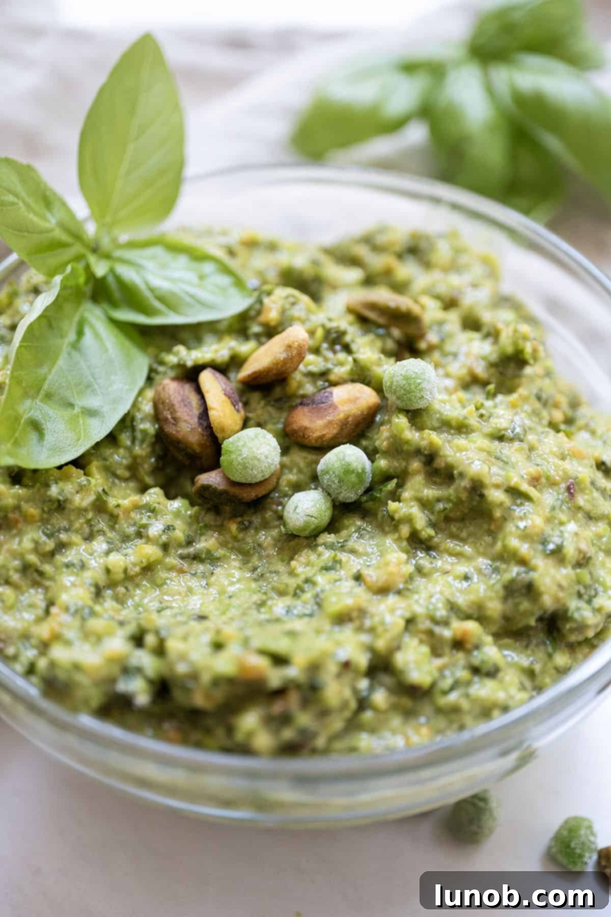 Sweet Pea and Basil Pesto 2 Pea pesto topped with pistachios and basil in a small bowl.