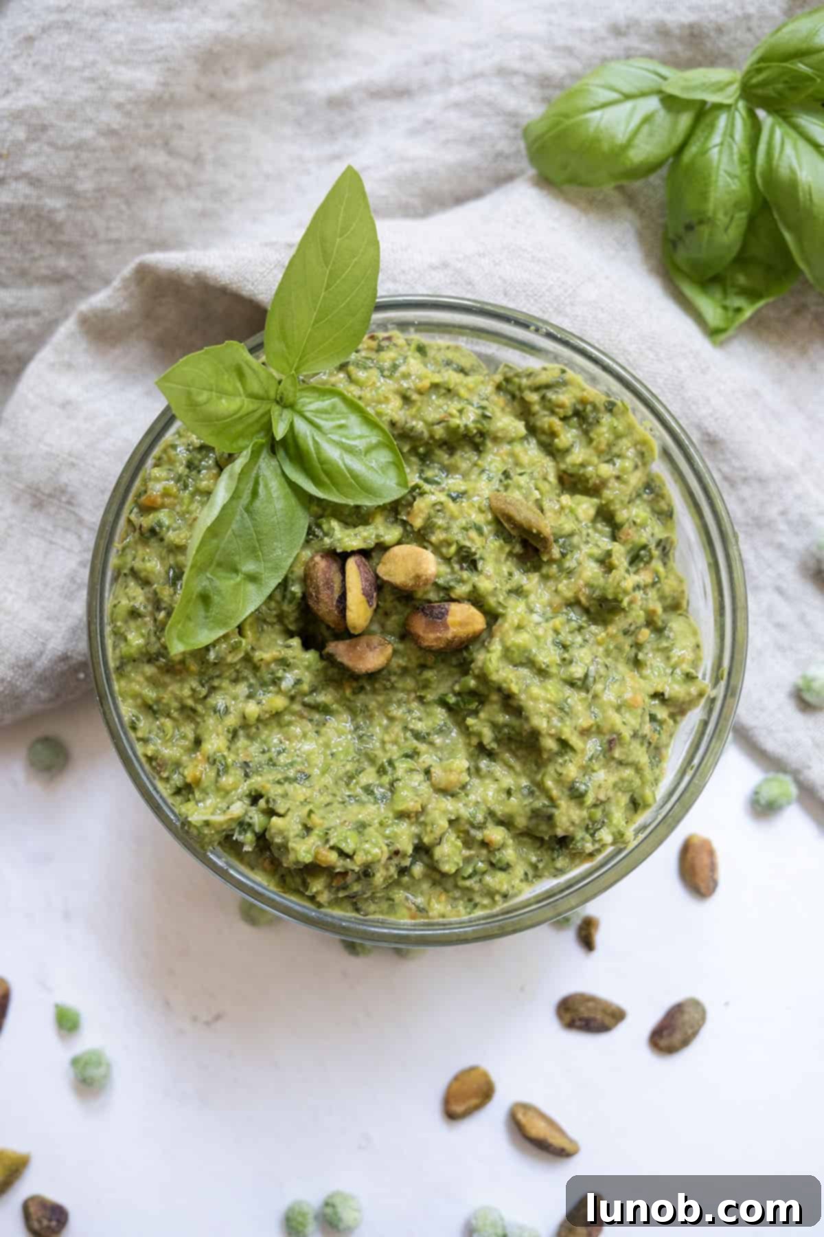 Sweet Pea and Basil Pesto 8 Pea pesto topped with pistachios and basil in a small bowl.