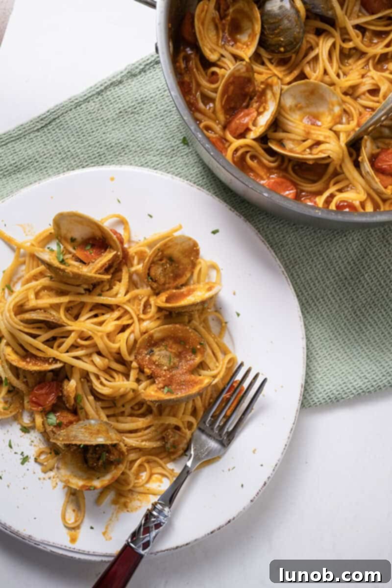 A close-up of a plate of linguine with clams in red sauce, showcasing the vibrant colors and texture, garnished with fresh herbs and golden breadcrumbs.