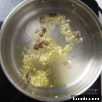 Garlic and anchovies sizzling in olive oil in a saucepan.