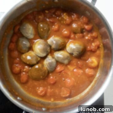 Fresh clams, still closed, simmering in the red tomato sauce.