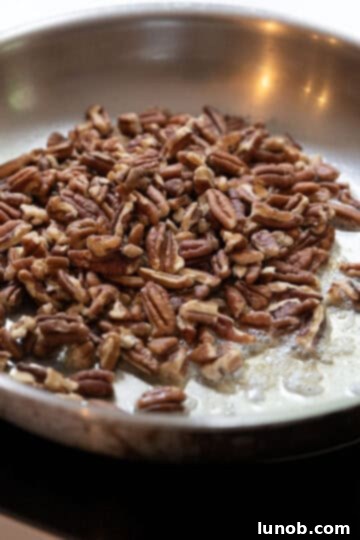 Honey Glazed Prosciutto Asparagus 6 Whole pecans being toasted in melted butter in a small saucepan.