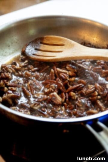 Honey Glazed Prosciutto Asparagus 7 Brown sugar and vanilla caramelizing onto pecans in a saucepan, creating a sticky, glossy coating.