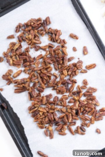 Honey Glazed Prosciutto Asparagus 8 Candied pecans spread out on a parchment-lined baking tray, ready for a final roast.