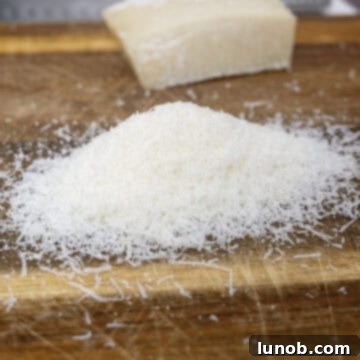 Pecorino Romano cheese freshly grated on a cutting board, prepared for the Amatriciana sauce.