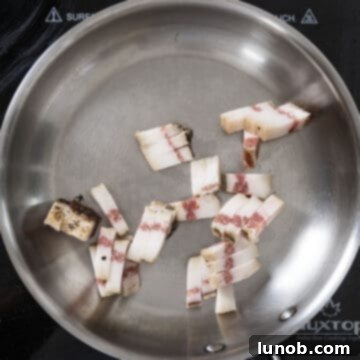 Guanciale strips placed in a cold frying pan, preparing to render fat over medium heat.