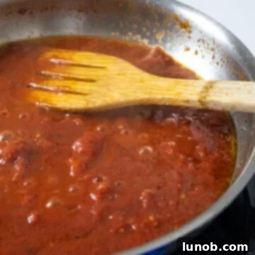 Black pepper freshly ground into the simmering tomato sauce, infusing flavor.
