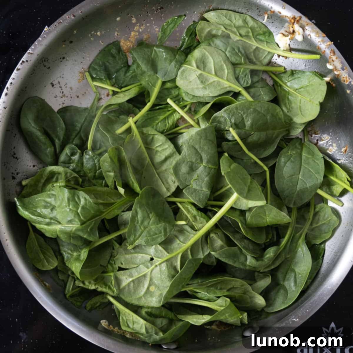 Sauteing spinach in a pan.