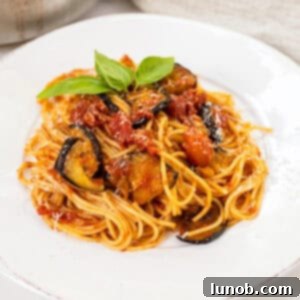 Pasta alla norma plated on a dish and garnished with basil.