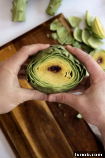 Tender Steamed Artichokes Made Simple 4 Top part of an artichoke being cut off with a knife.