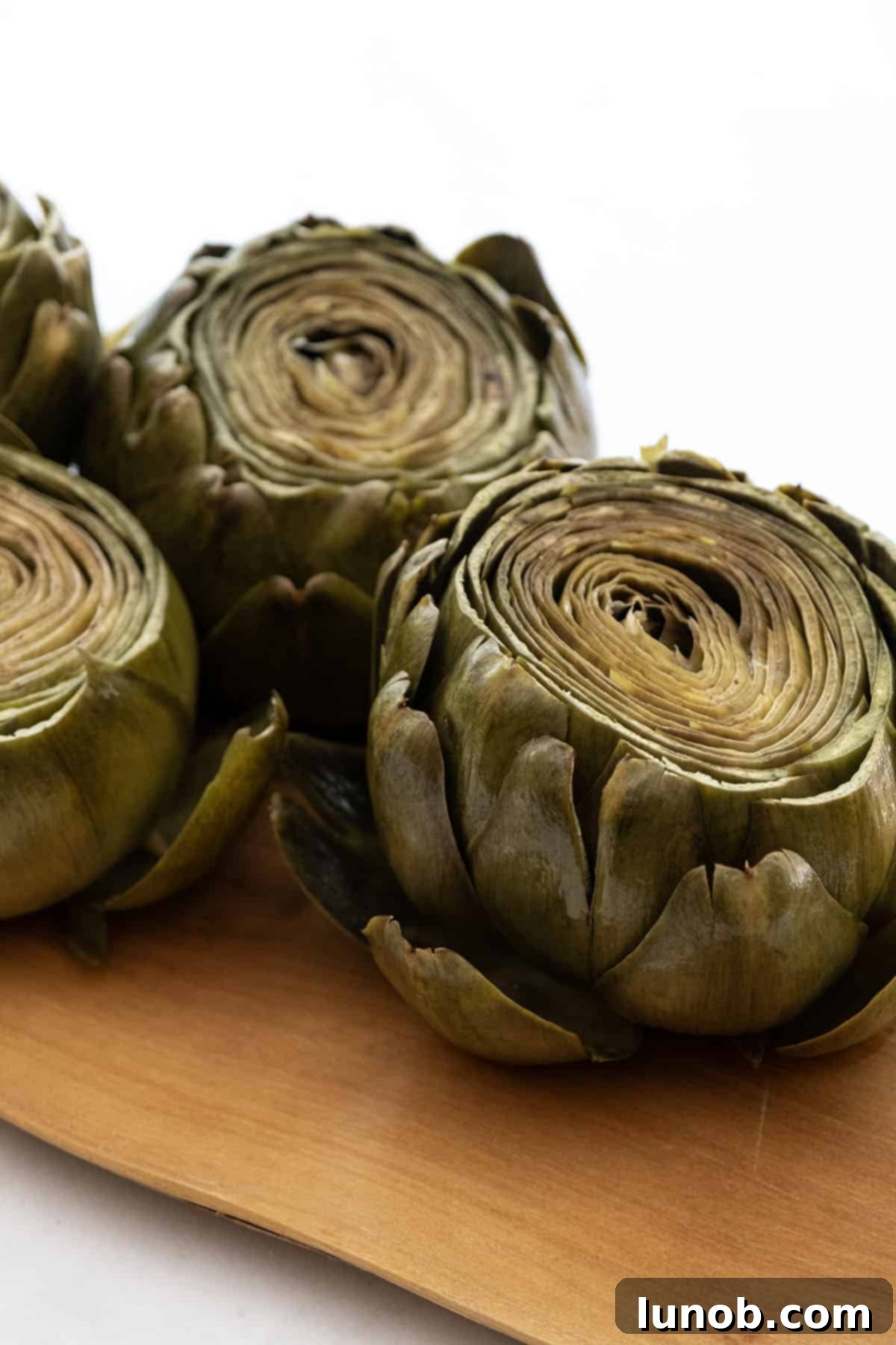 Tender Steamed Artichokes Made Simple 7 A close-up shot of a plate of steamed artichokes, with some leaves pulled.