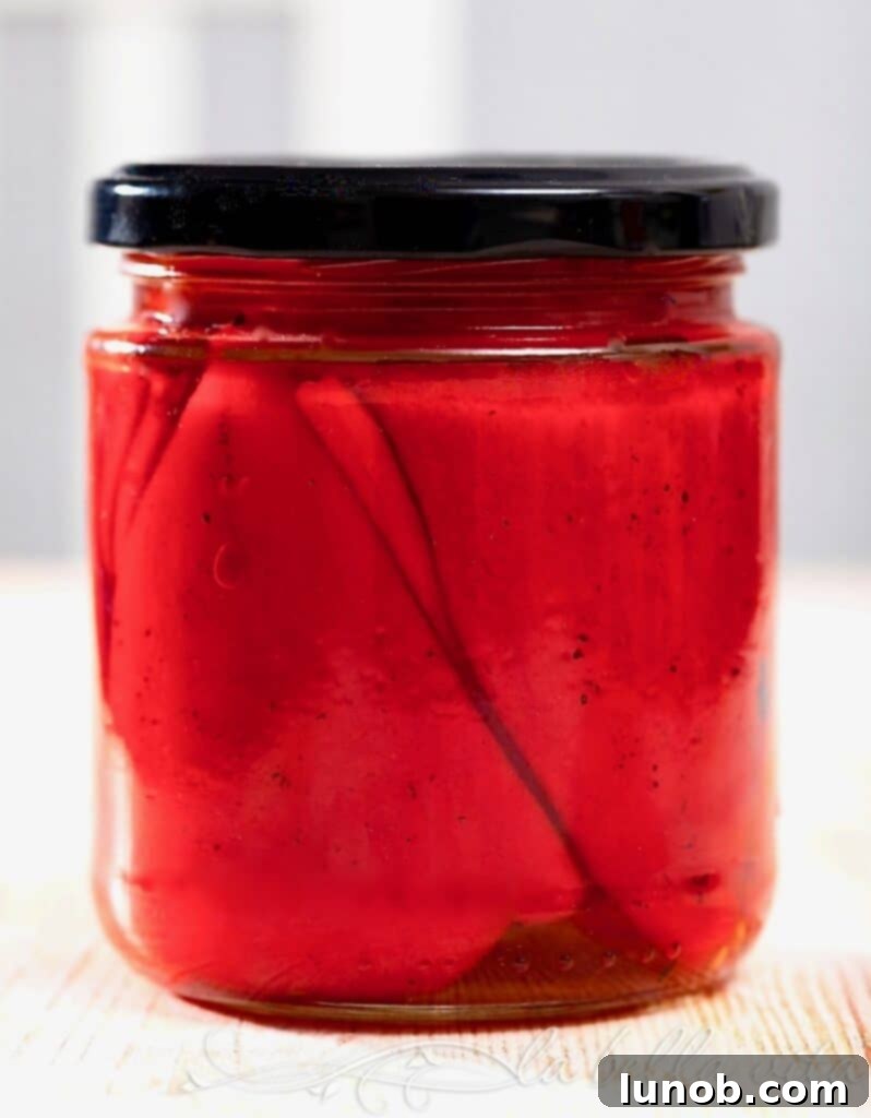 Perfectly Roasted Red Peppers: Freeze for Future Flavor 9 A jar of roasted red peppers soaking in olive oil, with herbs and capers for flavor