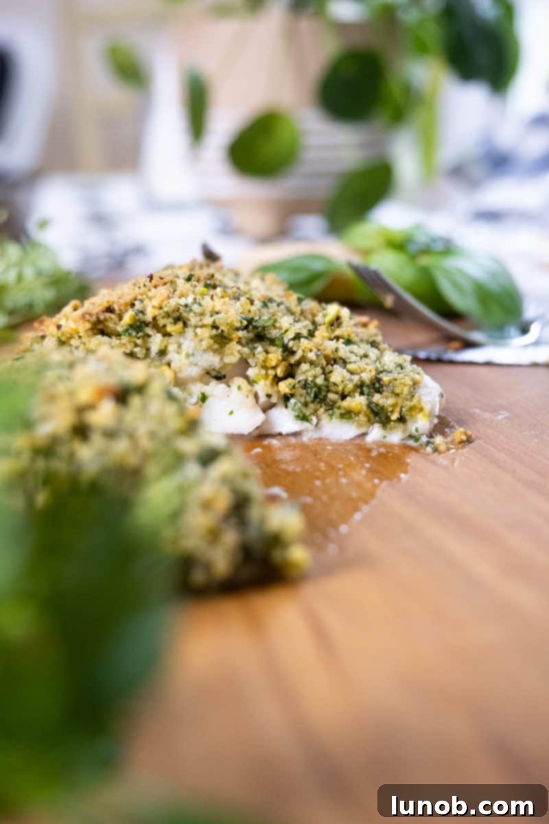 Golden Pistachio-Crusted Fish 4 Low-profile picture of pistachio crusted sea bass on a wooden board, garnished.