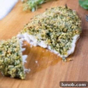 Golden Pistachio-Crusted Fish 5 Pistachio crusted sea bass cut in half on a cutting board, ready to serve.