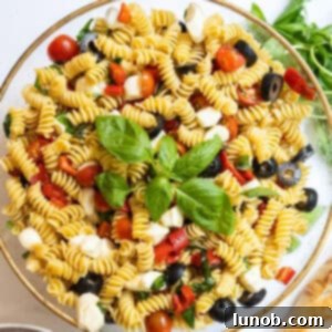 Italian pasta salad in large bowl garnished with basil.