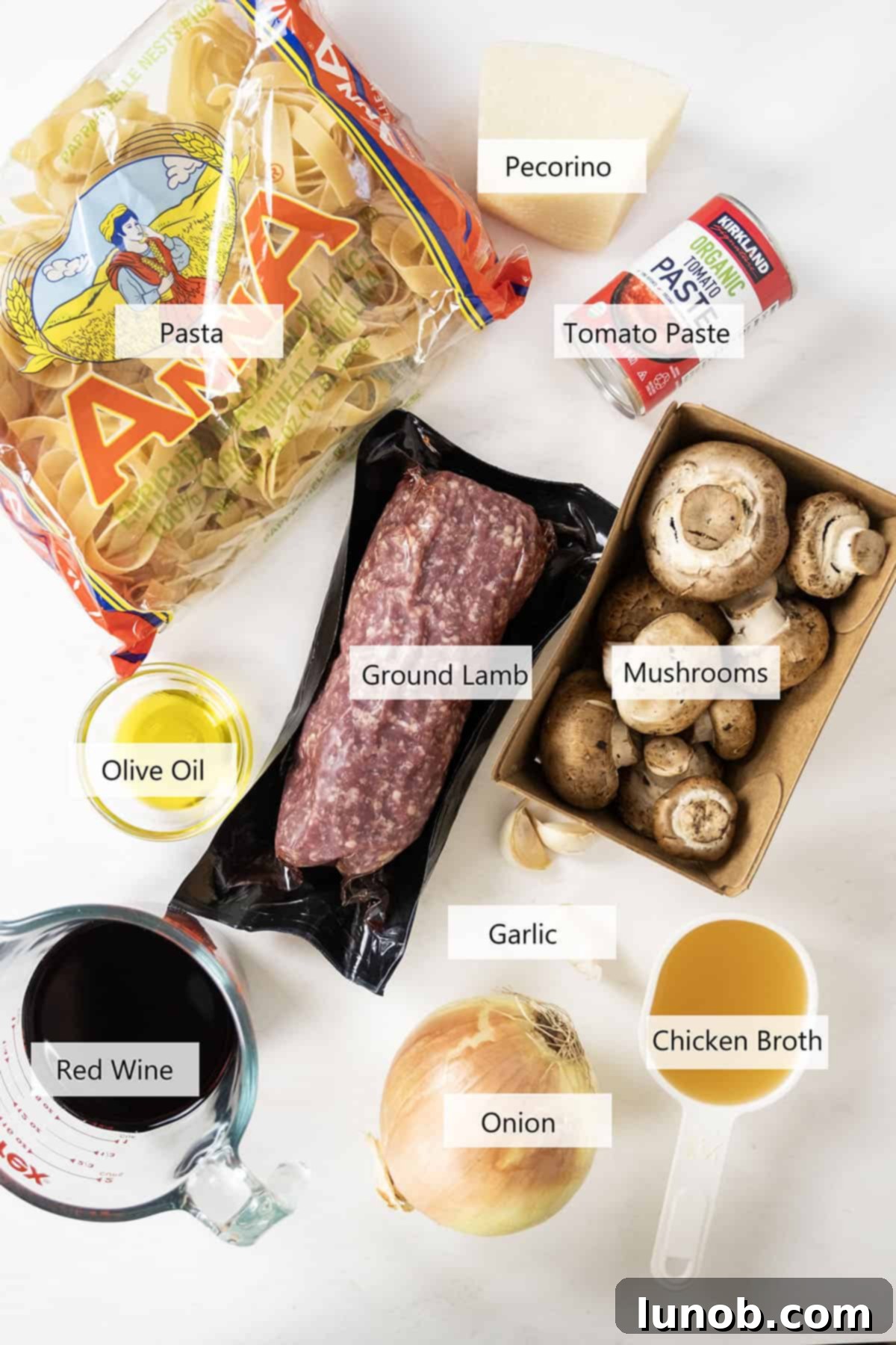 Fresh ingredients for quick lamb ragu, including ground lamb, pappardelle, vegetables, and Pecorino Romano.