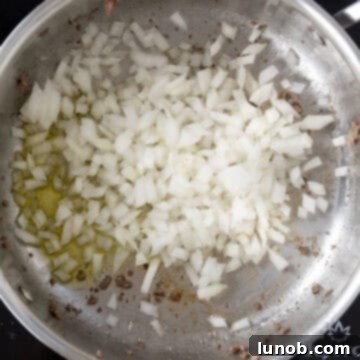 Finely minced onions sautéing in olive oil in a saucepan, turning translucent and golden.