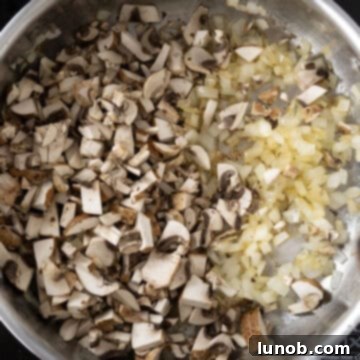 Sautéed onions combined with chopped mushrooms in a saucepan, cooking until softened.