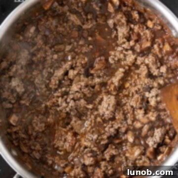 Cooked lamb returned to the saucepan, simmering gently in the rich ragu sauce.