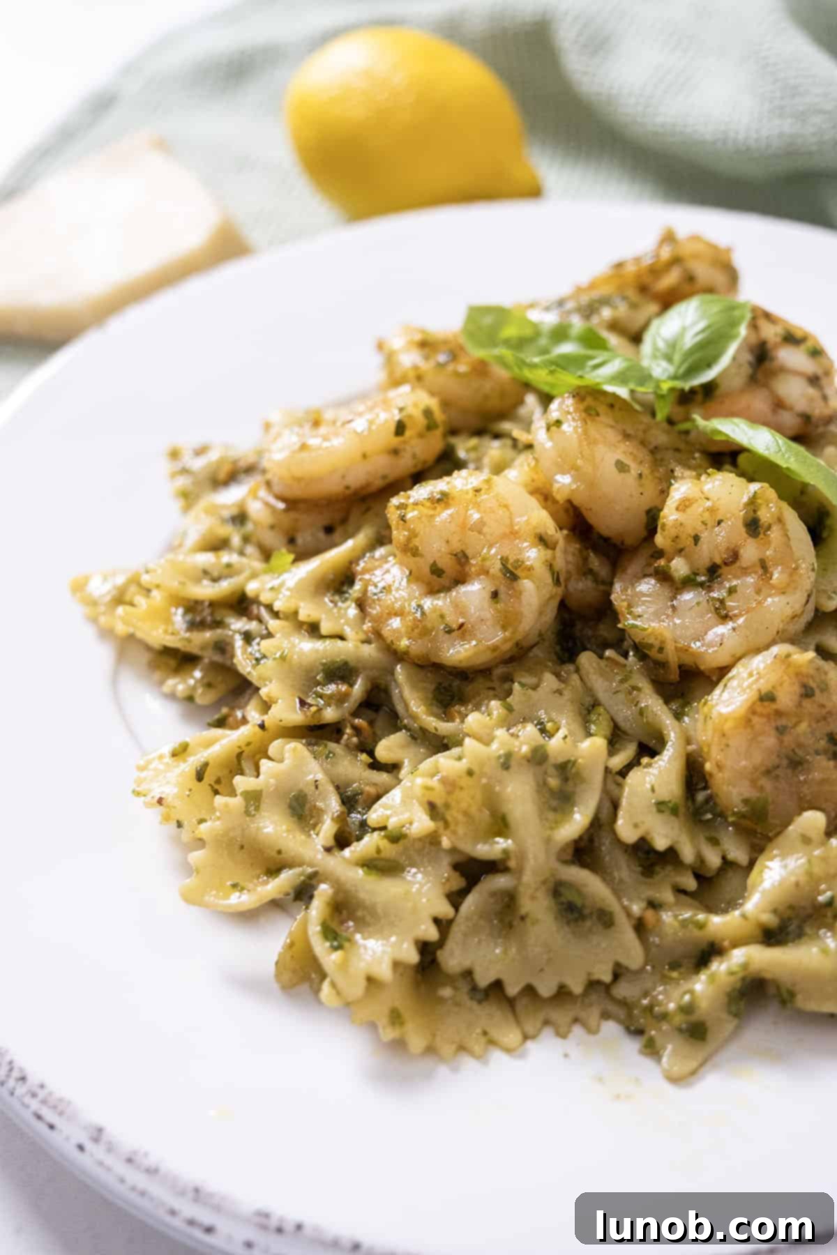 Silken Pesto Shrimp Delight 2 Freshly cooked shrimp pesto pasta garnished with bright green basil leaves in a bowl.