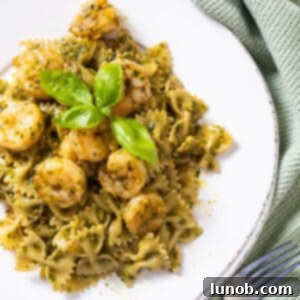 Silken Pesto Shrimp Delight 10 Creamy pesto shrimp pasta garnished with fresh basil leaves in a serving bowl.