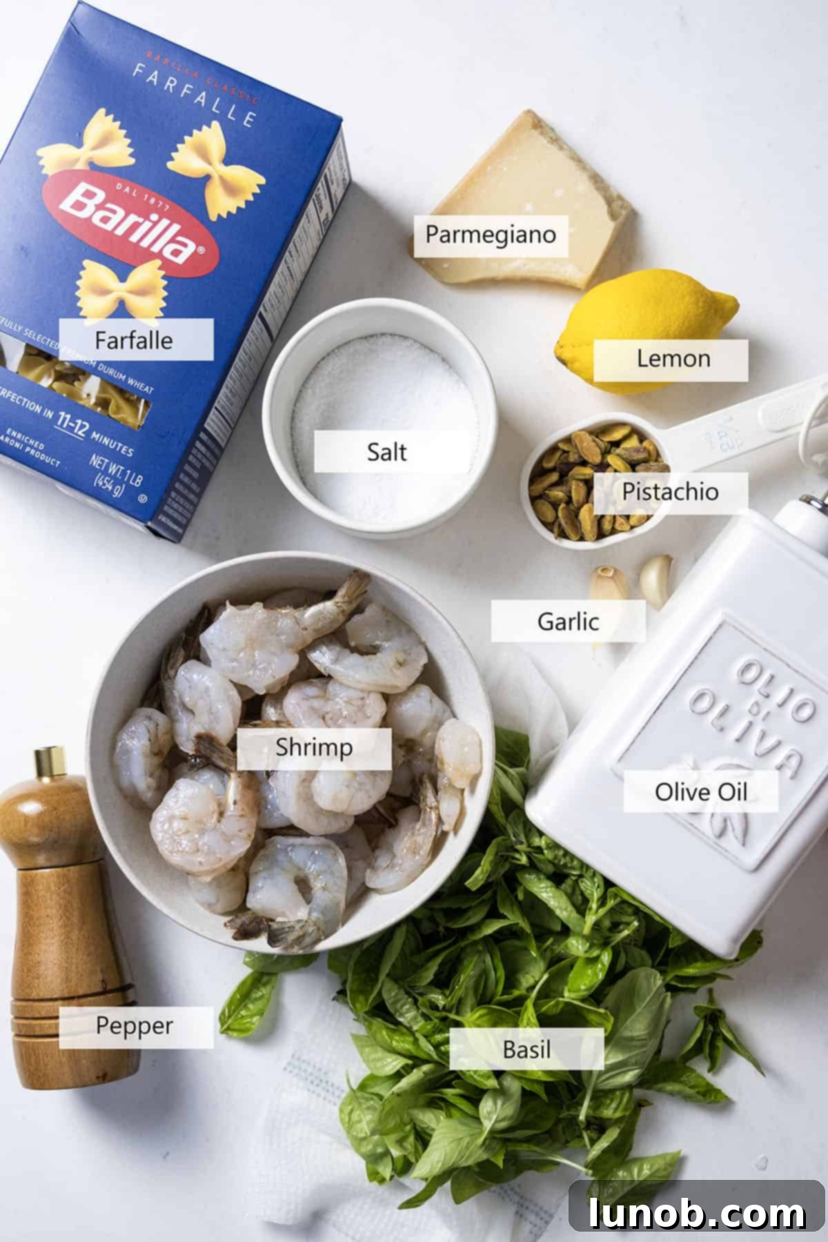 Silken Pesto Shrimp Delight 3 Fresh ingredients laid out for creamy pesto shrimp pasta, including raw shrimp, basil, pasta, garlic, lemon, and olive oil.