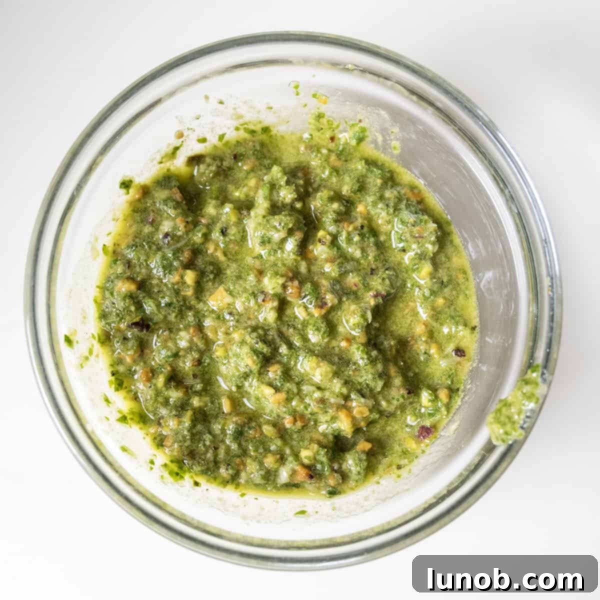 Silken Pesto Shrimp Delight 4 Freshly blended green pesto in a clear glass bowl, showcasing its rich texture.