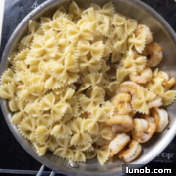Silken Pesto Shrimp Delight 7 Al dente farfalle pasta and seared shrimp being combined in a large saucepan.