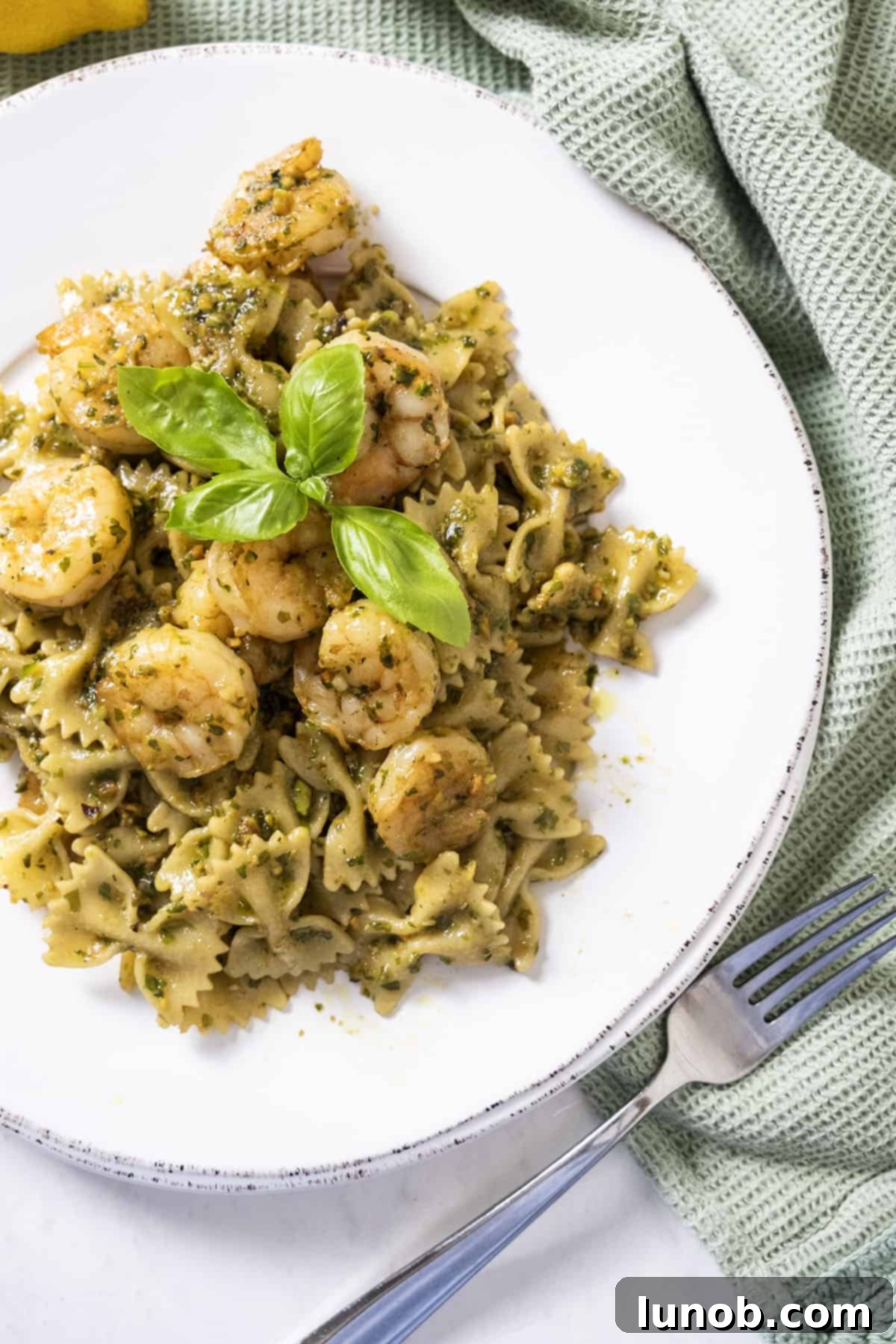 Silken Pesto Shrimp Delight 9 Close-up of creamy pesto shrimp pasta, with perfectly cooked shrimp and fresh basil leaves as garnish.