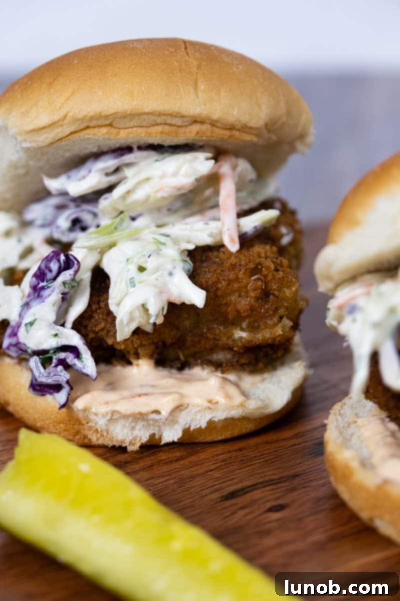 Crunchy Catch Sliders 3 Crispy fish slider topped with creamy coleslaw and a drizzle of chipotle mayo, presented beautifully on a platter